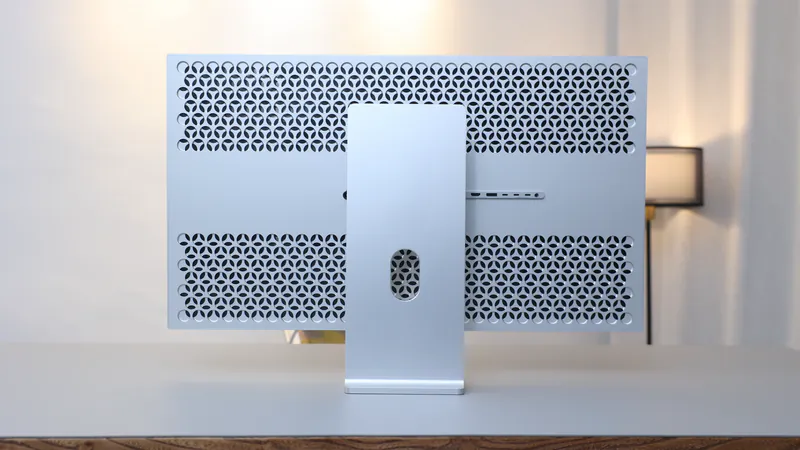 Dos perforé de l'écran Kuycon G32P posé sur un bureau, avec son pied argenté et la rangée de connecteurs