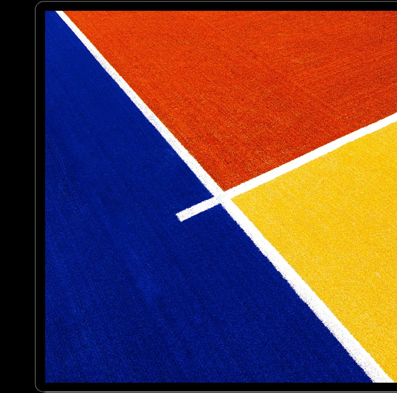 Écran Kuycon P27Z sur fond noir affichant des aplats orange, jaune et bleu vifs séparés par des lignes blanches, pour illustrer la richesse des couleurs